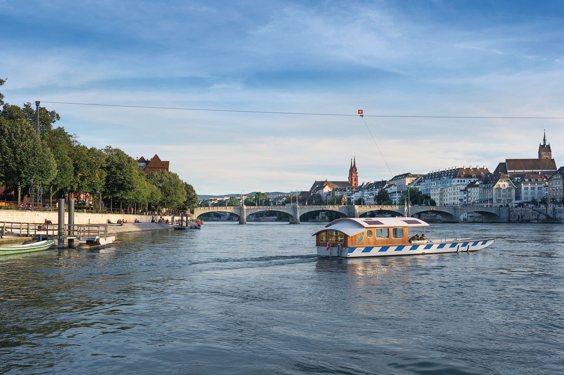 Auf den vier Basler Fähren (hier die Münsterfähre «Leu») lässt sich der Rhein bequem und nur durch die Kraft der Strömung überqueren.
///
The four ferries that cross the river using only the natural power of the river's current connect the larger southern part of the city (Grossbasel) with the northern side of the river (Kleinbasel).