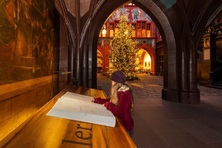 Im Innenhof des Basler Rathauses liegt jedes Jahr das Wunschbuch auf, um all das in sich aufzunehmen, was sich die Bevölkerung und die Gäste aus aller Welt in der Adventszeit wünschen.
  ///  
Every year the traditional Basel Wish Book is openly accessible in the inner courtyard of the Town Hall for all members of the public – both local residents and visitors from around the world – to add their Advent wishes