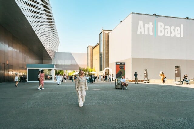 Die Künstlerin Sophie Lardon  läuft den Messenplatz entlang. Im Hintergrund sieht man eine Messehalle mit dem Art Basel Logo drauf.