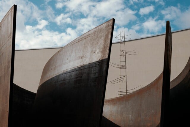 Gebogene Metallwände vor einem Gebäude. Kunstwerk Intersection von Richard Serra in Basel